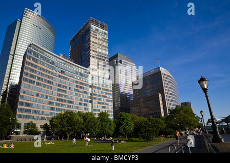 Familien genießen Sie einen Sommertag Ball spielen und entspannen auf einer Rasenfläche vor der moderne Gebäude in Battery Park City. Stockfoto