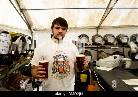 Eine Bar Arbeitnehmer halten zwei Pints Ale am Hoop Beer Festival in Essex. Foto von Gordon Scammell Stockfoto