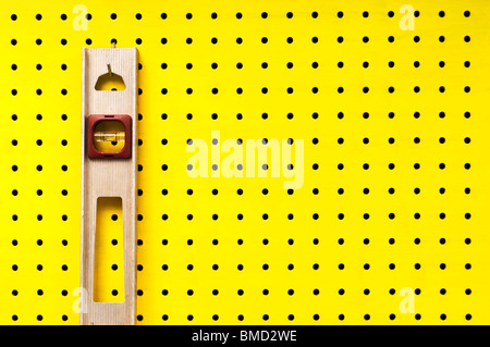 Alte Stufe hängt von einem Haken an gelbe Pegboard. Stockfoto