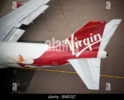 Die Schwanzflosse und Firmenlogo eines Virgin Atlantic Airbus A340-300 Flugzeugen auf dem Rollfeld am Flughafen London Heathrow Stockfoto