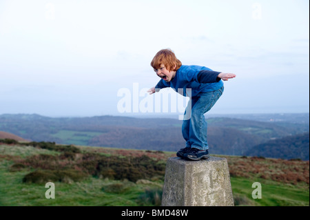 6-jähriger Junge balancieren auf einen trigonometrischen Punkt bei Sonnenuntergang in Caerphilly South Wales Stockfoto