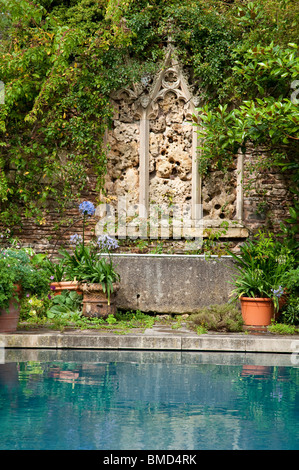 Stein-Funktion Kirchenfenster, mit Schwimmbad im Vordergrund, jüngere Court Gardens, Cotswolds, UK Stockfoto