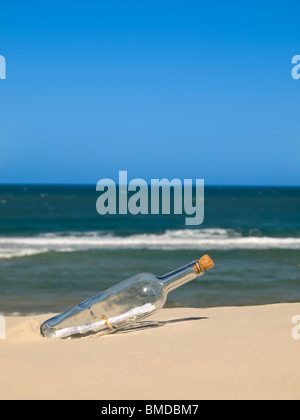 Eine Flasche mit einer Nachricht im Inneren wird am Strand begraben. Stockfoto