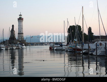 Lindauer Hafeneinfahrt, Yachthafen und Leuchtturm am Bodensee in Deutschland in der Abenddämmerung mit Spiegelungen im Wasser Stockfoto