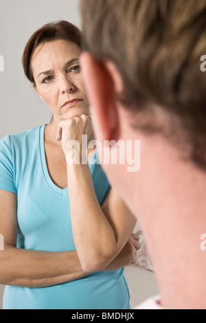 Frau mit der Hand unter Kinn Blick auf Menschen Stockfoto