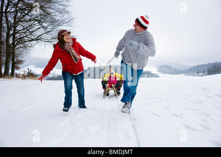 Eltern ziehen Kinder in Schlitten im Winter Stockfoto