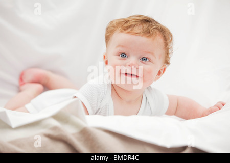 Ein 6 Monate altes Baby Boy Verlegung auf Händen und Knien auf einem weißen Hintergrund Blatt Stockfoto