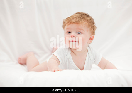 Ein 6 Monate altes Baby Boy Verlegung auf Händen und Knien auf einem weißen Hintergrund Blatt Stockfoto