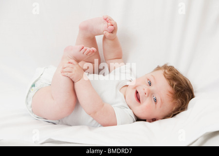 Ein 6 Monate altes Baby Boy Verlegung auf seinem Rücken auf einem weißen Hintergrund Blatt Stockfoto