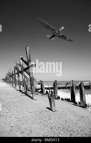 Eine alte kleine Flugzeuge fliegen über gebrochene Meer Abwehrkräfte. Stockfoto