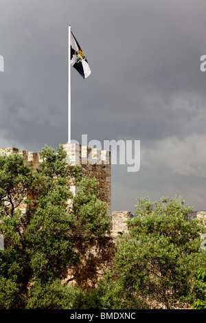 Eine Flagge auf den Zinnen des Sao Jorge Castle in Lissabon, Portugal, gegen einen stürmischen Himmel. Stockfoto