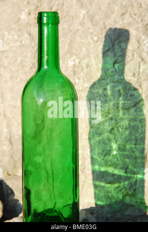 Grüne Flasche Wein und seinen Schatten auf die Felswand Stockfoto