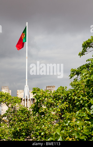 Eine Flagge auf den Zinnen des Sao Jorge Castle in Lissabon, Portugal, gegen einen stürmischen Himmel. Stockfoto