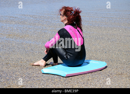eine junge Frau sitzt auf einem Bodyboard am fistral Beach, Newquay, Cornwall, uk Stockfoto