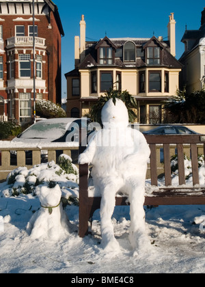 Schneemann mit seinem Schnee Hund neben ihm sitzen auf einer Bank sitzend Stockfoto