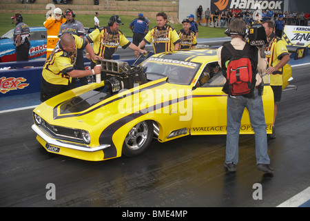 Australische Top Doorslammer Drag Racer, Stuart Bishop, sitzt auf der Startlinie während seiner Boxencrew seinen aufgeladenen Camaro vorbereiten Stockfoto