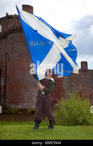 Frau Fahnenträger Covenantar schwenkt große schottische covenanters Flagge auf Caerlaverock Castle historische mittelalterliche Festung in Dumfries, Schottland, Großbritannien Stockfoto