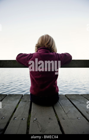 Mädchen sitzen auf Steg Stockfoto