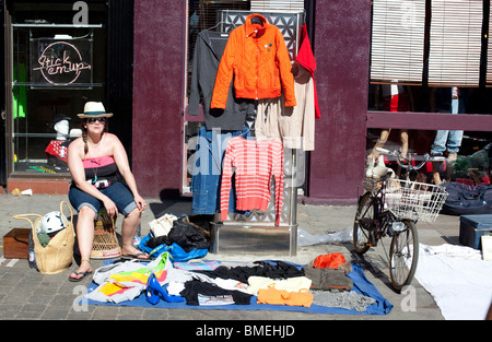 Frau, die Second-Hand-Kleidung verkauft, auf dem Brick Lane Market, Spitalfield, London, England, Großbritannien. Stockfoto