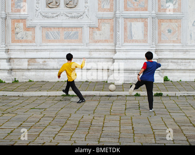 Italienische Kinder spielen Fußball durch eine Kirche in Venedig, Italien Stockfoto