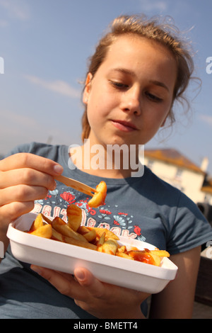 Teenager-Mädchen einen Teil der Späne aus einem Plastikbehälter mit hölzernen Form im Freien zu essen Stockfoto