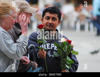 Touristen abbürsten ein Mann verkauft Rosen in Markusplatz entfernt, Venedig, Italien Stockfoto