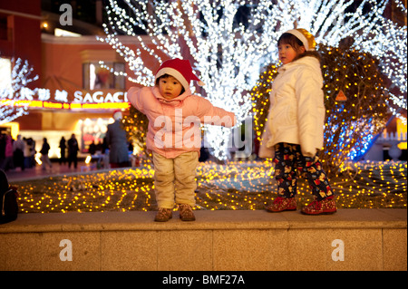 Zwei kleine chinesische Mädchen mit Weihnachtsmütze spielen im Solana Lifestyle Shopping Park am Heiligabend, Peking, China Stockfoto