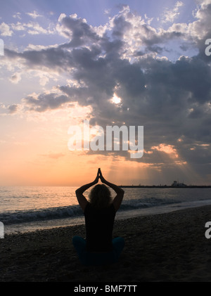 Frau praktizieren Yoga am Strand bei Sonnenuntergang. Stockfoto