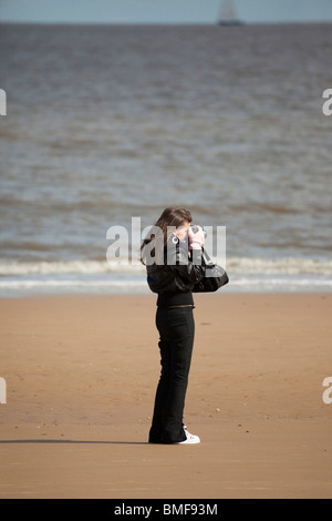 junge Frau, die eine Aufnahme an einem Strand in UK Stockfoto