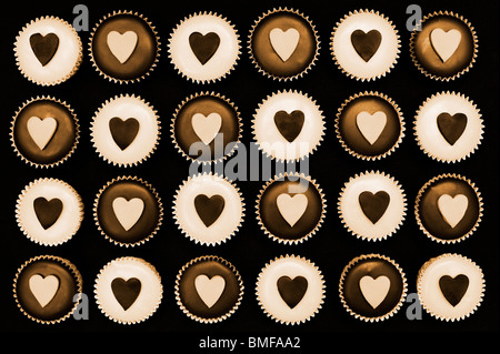 Mini-Muffins mit Herzformen verziert. Sepia-Farbton Stockfoto