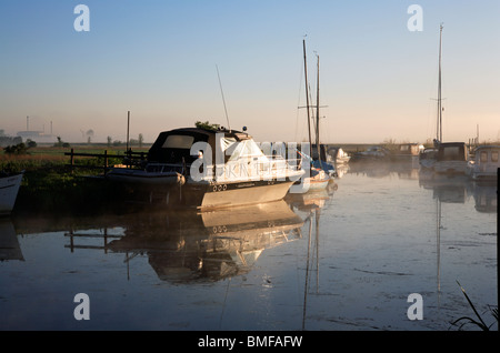 Festgemachten Sportboote am Hardley Staithe, Norfolk, England, im frühen Morgennebel und Sonnenlicht. Stockfoto