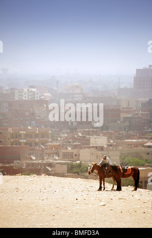 Pferde und ihre Reiter am Rande der Gizeh-Plateau, Dunst über Cairo Stadt im Hintergrund, Gizeh, Kairo, Ägypten Stockfoto