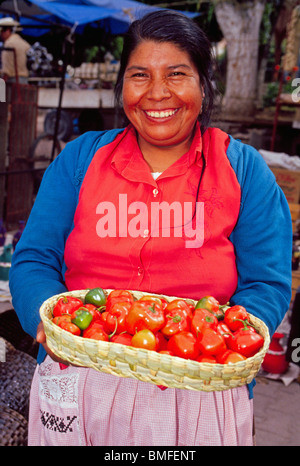 Eine fröhliche Frau verkauft Manzano Rojo (rot) Paprika im Freien auf dem beliebten Tonala Dorfmarkt in Guadalajara, Jalisco Staat, Mexiko. Stockfoto
