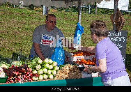 Frau kaufen frisches Obst und Gemüse aus einem Stall Inhaber bei ein Bauernmarkt, Clarkston, Glasgow, Schottland Stockfoto