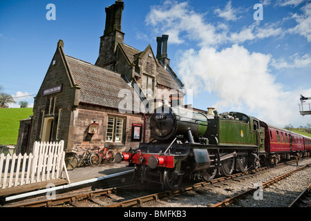 Ein Dampfzug durchläuft Cheddleton Station auf der Churnet Valley Railway. Stockfoto