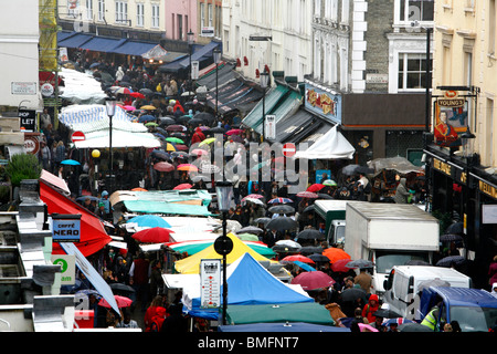 Käufer Schutz unter Sonnenschirmen, wie sie entlang der Portobello Road Market, Portobello Road, Notting Hill, London, UK Fuß Stockfoto