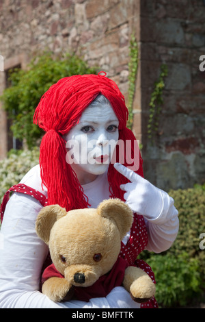 Women's Clown Rag Doll Fancy Dress. Eine furchtsame Frau mit roten Perücke gekleidet, und weiß bemaltem Gesicht, in Muncaster Castle, Cumbria, England, Großbritannien Stockfoto