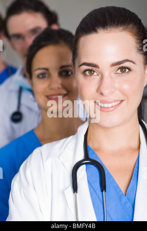 Ärztin in einem Krankenhaus mit ihrem Team hinter Lächeln Stockfoto