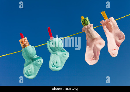 Baby Socken auf der Wäscheleine mit Euro-Banknoten. Blauer Himmel. Stockfoto