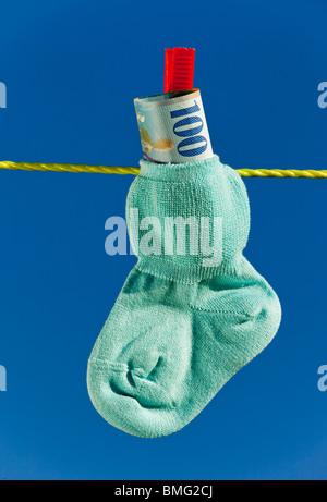 Babysocken auf Wäscheleine und Schweizerfranken. Blauer Himmel. Stockfoto
