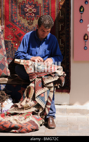 Türkei Antalya - Experte bei der Reparatur und Wiederherstellung der alten Kelim gewebt Teppiche und decken Werke vor seinem Geschäft Stockfoto