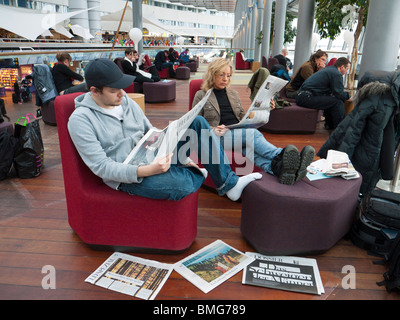 Reisende auf dem Flughafen Stockholm-Arlanda lesen Zeitungen während des Wartens auf ihr Flugzeug. Stockfoto