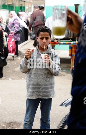 kleiner Junge trinken Zuckerrohrsaft, Souk Goma (Freitagsmarkt), Wochenmarkt, südliche Friedhöfe, Khalifa Bezirk, Kairo Stockfoto