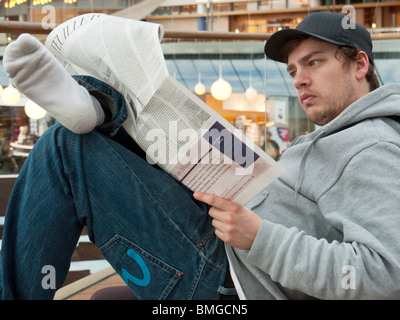 Ein Schüler liest eine Zeitung auf dem Flughafen Stockholm-Arlanda. Stockfoto