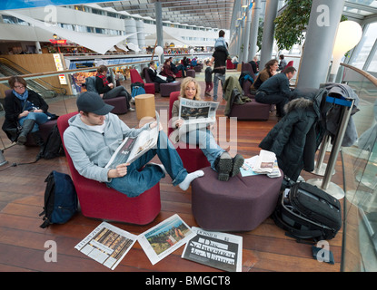 Reisende auf dem Flughafen Stockholm-Arlanda lesen Zeitungen während des Wartens auf ihr Flugzeug. Stockfoto