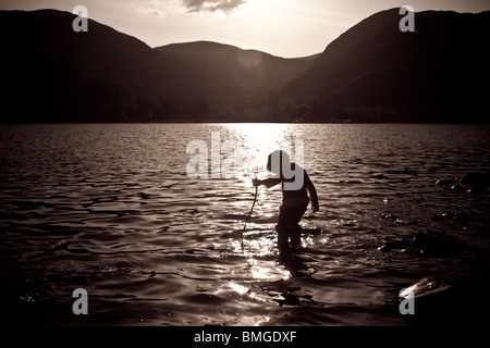 Silhouette eines Kindes spielt in dem See Ullswater Stockfoto