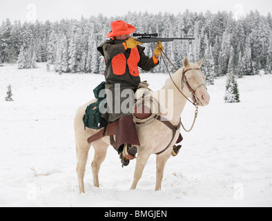 Deer Hunter White Reitpferd im Schnee mit dem Ziel, Gewehr Stockfoto