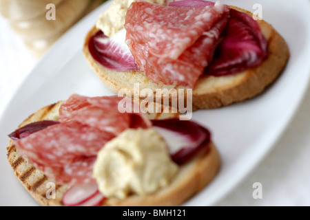 Milano Salami auf Bruschetta mit Houmous Stockfoto