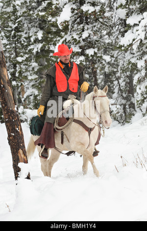 Cowboy Jäger weiß Reitpferd im Schnee jagen Stockfoto