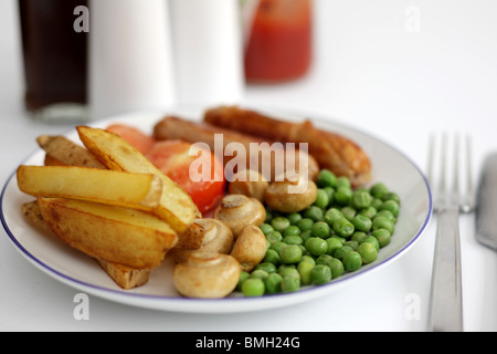 Frisch gekochte Mahlzeit von Wurst aus Schweinefleisch mit Chips Erbsen, Champignons und Tomaten auf einem Tisch mit Keine Personen Stockfoto